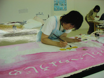 子供が絵本の絵を大きな布や紙に描いている写真